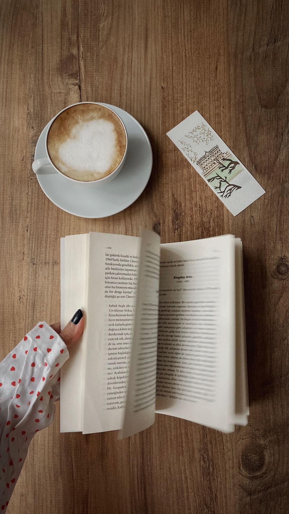 Top-down flat lay of a latte with leaf art, a cookie, and a book titled Rooted Together